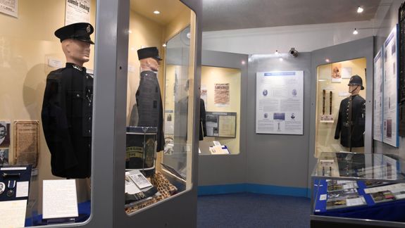 Display cases at the Glasgow Police Museum showing historic police uniforms, documents, and artifacts.