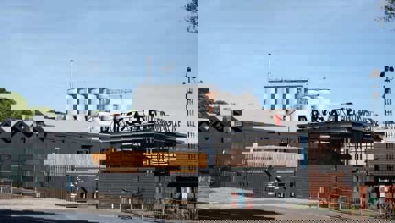 Exterior view of Drygate Brewery with modern dark grey buildings and large silver brewing tanks in the background