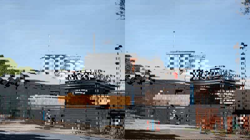 Exterior view of Drygate Brewery with modern dark grey buildings and large silver brewing tanks in the background