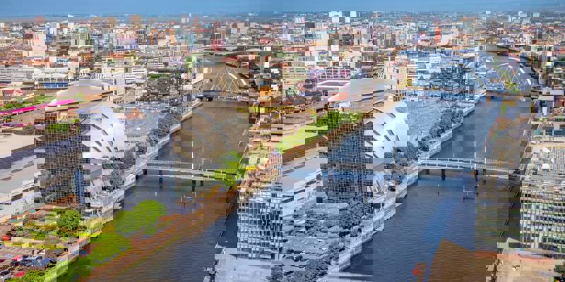 An aerial view of the River Clyde winding through Glasgow, with modern buildings and several bridges spanning the water.