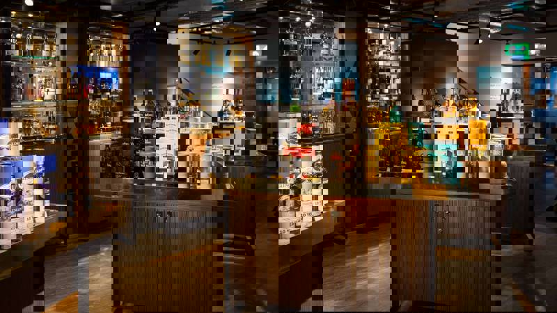 A spacious whisky shop with various bottles displayed on shelves and tables.