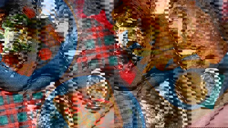 A rustic meal featuring a large plate of classic fish and chips with mushy peas, and two plates of salad and prawns on toast.