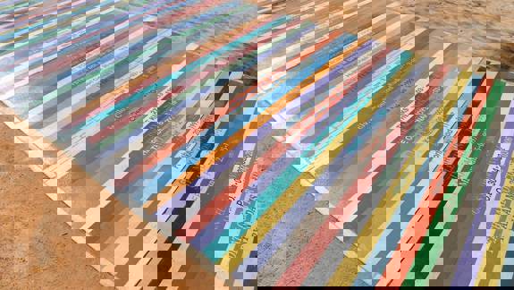 A ground-level artwork with colourful stripes, each labelled with a musician's name and a date.