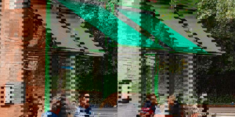 Outdoor seating at Bramble cafe with customers dining under a green awning.