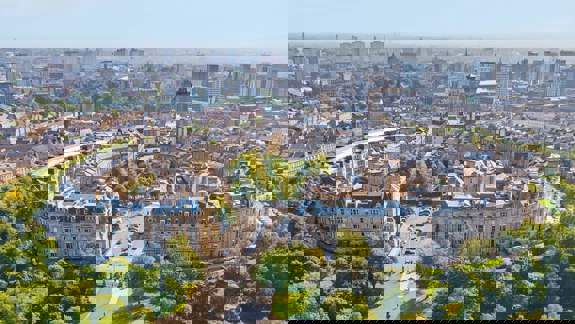 An aerial view of Park Circus, a crescent of historic buildings surrounded by green parkland in Glasgow.