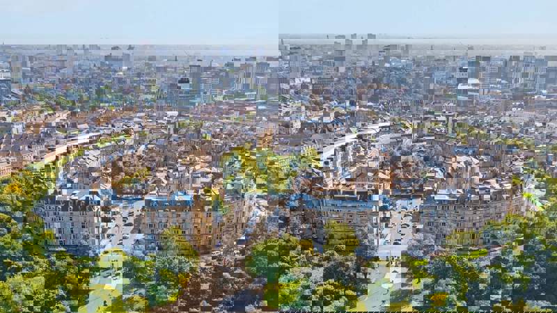 An aerial view of Park Circus, a crescent of historic buildings surrounded by green parkland in Glasgow.