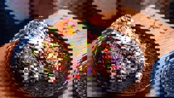 A beautifully presented dish of food at Ocho, a Glasgow restaurant, featuring a fried egg, avocado, and other toppings on a dark plate.