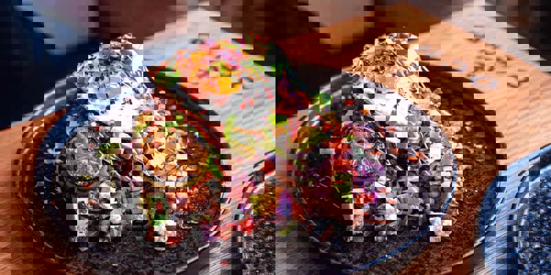 A beautifully presented dish of food at Ocho, a Glasgow restaurant, featuring a fried egg, avocado, and other toppings on a dark plate.