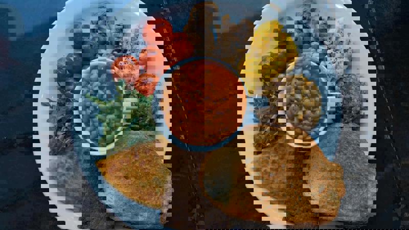 A plate of vegan full breakfast with beans, scrambled 'eggs,' tomatoes, mushrooms, and toast.