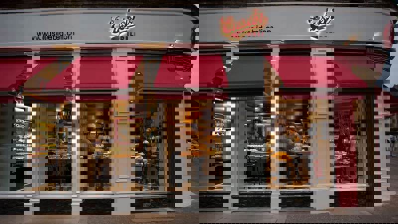 Exterior of Eusebi Deli with red awnings and visible diners inside.