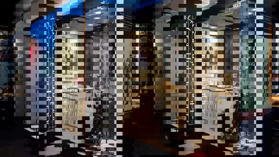 An interior view of the Bagpipe Museum (National Piping Centre), displaying various historical bagpipes and related artifacts in illuminated glass display cases.