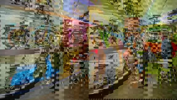 Visitors explore the Riverside Museum, looking at displays of vintage cars, motorcycles, and public transport vehicles.