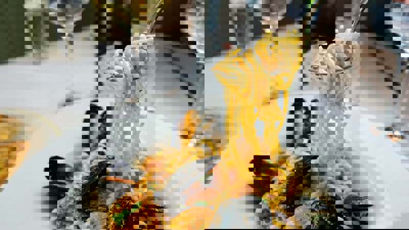 Fork lifting spaghetti with mussels from a plate in an Italian restaurant.